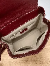 Mochila de cuero vacuno marrón con acabado pulido, solapa en forma de V y costuras decorativas. Cuenta con cremalleras laterales y asas ajustables.