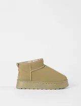 Botas cortas tipo ugg color beige, con interior forrado en corderito sintético y suela de plataforma plana.