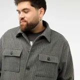 Sobrecamisa gris de corte recto con diseño de rayas verticales finas, cuello clásico, cierre frontal de botones y dos bolsillos delanteros con solapa y botón.