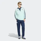 Pantalón deportivo Adidas de la colección Originals, inspirado en la selección de fútbol de Alemania. Es de color azul marino con las icónicas tres tiras laterales en color celeste. Presenta el escudo de la selección alemana en el muslo derecho y un corte clásico con cintura elástica y cordón de ajuste.