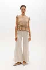 Pantalón palazzo de lino a rayas verticales color beige y blanco, de tiro alto y corte amplio.
