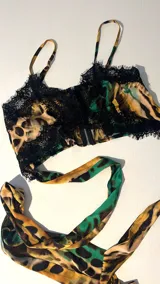 Top corto con estampado animal print en tonos verde y negro, con detalles de encaje negro en el escote y ruedo.