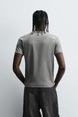 Camiseta gris de corte slim fit, confeccionada en tejido de algodón con elasticidad, cuello redondo y manga corta.