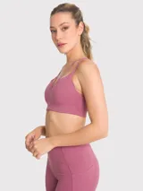 Top deportivo color rosa viejo con tirantes finos y detalle de tiras cruzadas en el frente. Cuenta con soporte medio y almohadillas removibles.