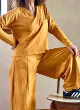 Conjunto de dos piezas compuesto por un buzo de cuello en V con bolsillo frontal y un pantalón tipo palazzo de corte evasé y pierna ancha. Confeccionado en tejido rústico de algodón con efecto batik.