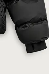 Cazadora puffer acolchada de corte relaxed fit color negro, confeccionada en tejido técnico repelente al agua. Cuenta con cuello subido, capucha ajustable con elásticos y cierre frontal con cremallera. Tiene bolsillos de vivo en la cadera, bolsillo interior y mangas largas con puños elásticos ajustables con abertura para el dedo pulgar.