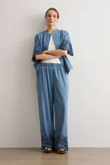 Pantalón de jean de corte holgado y pernera ancha, con cintura elástica y detalle de bordado oscuro con diseño floral y perforaciones en el bajo.