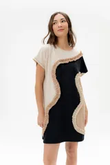 Vestido corto de algodón, con bloques de color en tonos pastel (amarillo claro, beige y rosado pálido) unidos por volados fruncidos en tonos marrón claro y amarillo. Presenta cuello redondo y mangas cortas.