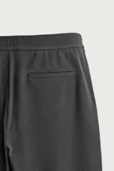 Pantalón negro confeccionado en mezcla de algodón, con cintura elástica, bolsillos frontales y cierre con cremallera y botón.