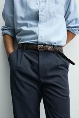 Pantalón de corte recto confeccionado en tejido elástico, con cintura elástica, pliegues frontales, bolsillos laterales y bolsillos traseros de vivo con botón.