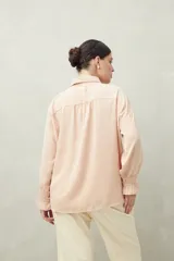 Camisa negra de manga larga con cuello clásico y botones frontales. El tejido presenta una textura arrugada o plisada, y los puños tienen un frunce elástico.