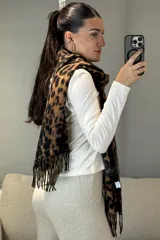 Bufanda rectangular con estampado animal print de leopardo en tonos marrones y negros, con terminación de flecos en los extremos.
