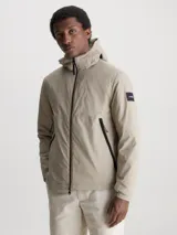 Campera beige con capucha, cierre frontal con cremallera, bolsillos laterales con cremallera y logo de Calvin Klein en la manga.