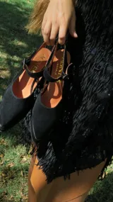 Sandalias de gamuza color beige con punta fina reforzada con detalle metálico, taco cuadrado y pulsera ajustable al tobillo.