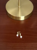 Aros colgantes de plata 925 con baño de oro 18k, diseñados con una tira de tres zirconias cúbicas y una perla cultivada colgante en el extremo.