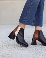 Botinetas de cuero con diseño tricolor en negro, marrón con textura croco y blanco. Presentan taco cuadrado, plataforma y cierre lateral.