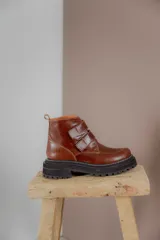 Borcego de cuero color suela con puntera redondeada, cierre mediante tiras de velcro y suela track de goma negra.