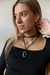 Collar con tiento negro y dije de piedra natural ovalada en tonos grises y azules.