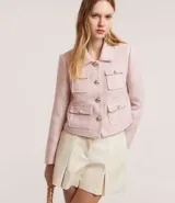 Campera corta de tweed color rosa, con cuello camisero, bolsillos delanteros con solapa y botones dorados estilo escudo.