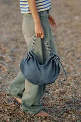 Bolso de hombro confeccionado en denim con efecto deslavado, diseño fruncido en los laterales con tiradores ajustables y asa de hombro combinada con cadena metálica plateada. Cuenta con cierre de cremallera y bolsillo interior.