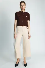 Pantalón culotte de tiro medio en color beige, con bolsillos de plastrón en el frente y costuras verticales. Incluye un cinturón trenzado fino en color marrón a contraste.