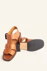 Sandalia de cuero vacuno texturado color negro, con tiras anchas y hebilla lateral. Taco ancho de madera.