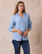 Blusa celeste de lyocell con cuello con solapa, escote en V y cierre con botones. Tiene un bolsillo en el pecho, mangas 3/4 con puño y botón.