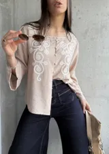Camisa beige de manga larga con bordado floral blanco en el frente y cuello mao.