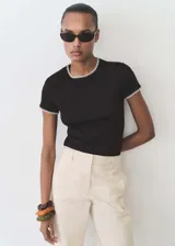 Camiseta negra de algodón con cuello redondo y mangas cortas con ribetes blancos en contraste.