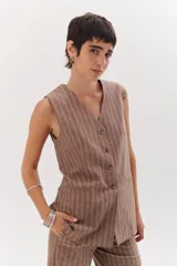 Chaleco marrón claro con rayas verticales blancas, escote en V y cierre frontal con botones.