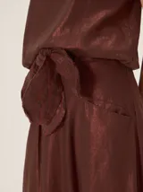 Falda midi color bordó con brillo sutil y detalle de lazo en la cintura.