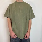 Remera de corte oversize en color verde oliva con efecto lavado, confeccionada en tela rústica pesada, con cuello redondo y bordes sin costura.
