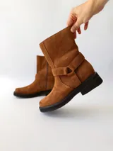 Bota corta de cuero color camel, con correa decorativa alrededor del tobillo y suela de goma negra.