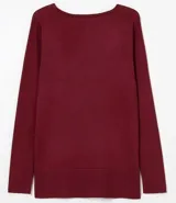 Suéter de punto color rosado, con cuello barco, mangas largas y puños con botones decorativos. El dobladillo también es acanalado.