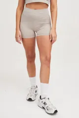 Calza corta color beige, de tiro medio y corte ajustado.