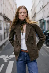 Blazer cruzado de mujer, color marrón oscuro, confeccionado en piel 100%. Presenta cuello solapa, manga larga con hombreras, bolsillos delanteros de doble vivo y cierre frontal cruzado con botones oscuros.