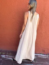 Vestido largo color beige, sin mangas, con cuello redondo y corte en A.