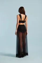 Vestido largo negro de fiesta, con corpiño estructurado, aberturas laterales en la cintura y falda larga semitransparente con detalles de encaje en el ruedo.