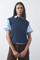 Chaleco de punto con textura afelpada, cuello redondo y hombros marcados. Presenta una silueta relajada y un diseño sin mangas.