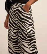 Pantalón wide de sarga con estampado animal print de cebra, cintura con trabilla, cierre tradicional y bolsillos cargo laterales.