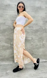 Pollera larga color beige con estampado de flores blancas y abertura lateral.