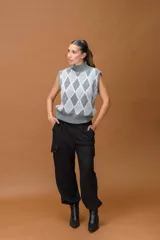 Chaleco tejido sin mangas con cuello alto, diseño de rombos en tonos grises y detalles de hilo lurex brillante.