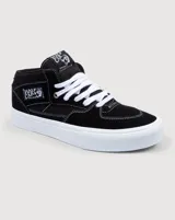 Championes de skate Vans modelo Half Cab, de corte medio, confeccionados en gamuza y lona color negro con costuras blancas. Presentan suela de goma blanca vulcanizada, cordones blancos y etiqueta distintiva en el lateral y la lengüeta.