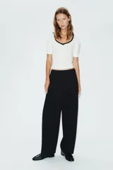 Camiseta blanca de manga corta y corte slim fit, con escote redondo ribeteado en negro, detalle de frunce en el centro del pecho y un pequeño lazo negro decorativo.