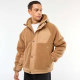 Campera con capucha color beige, con efecto borreguito en el cuerpo y las mangas, y detalles en tela lisa beige en los hombros y el pecho. Tiene cierre frontal y botones a presión.