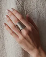 Anillo abierto de diseño rústico y orgánico, con textura irregular que evoca la naturaleza. Realizado artesanalmente en metal.