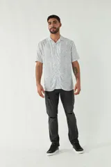 Camisa de manga corta con cuello cubano, confeccionada en viscosa con estampado de hojas en tonos azules. Presenta cierre frontal abotonado y corte slim.