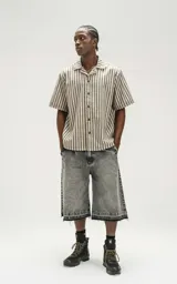 Bermuda de denim en color negro con efecto lavado, corte oversize y ruedo desflecado. Incluye un cinturón fino integrado en la cintura.