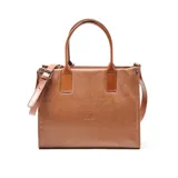 Cartera tipo tote de cuero texturizado color suela, con doble asa de mano y correa larga ajustable y extraíble. Presenta el logo de la marca grabado en el centro y cierre superior.