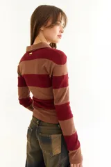 Top de manga larga con diseño de rayas horizontales en tonos negro y marrón, cuello polo con cierre de botones y bordado pequeño en el pecho.